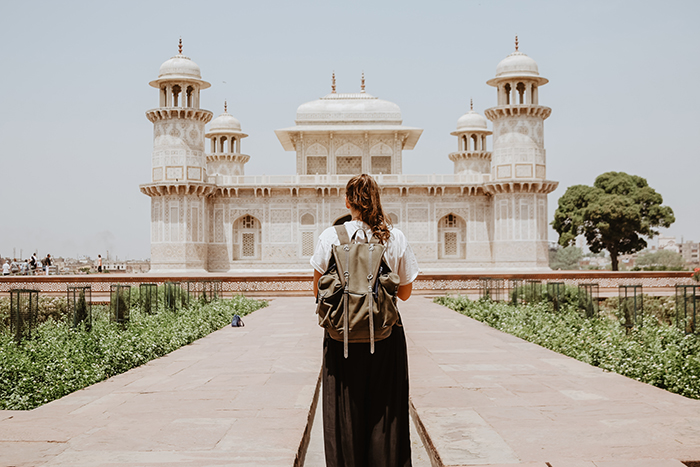 Person standing with a backpack looking at the Tomb of I'timad-ud-Daulah, in Agra, India