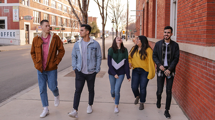 Group of students walking down a sidewalk talking