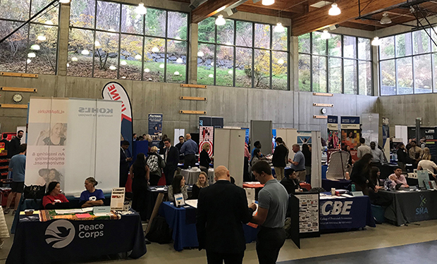 A career fair set up in the MAC Gym with vendor booths in rows and people walking around talking to recruiters