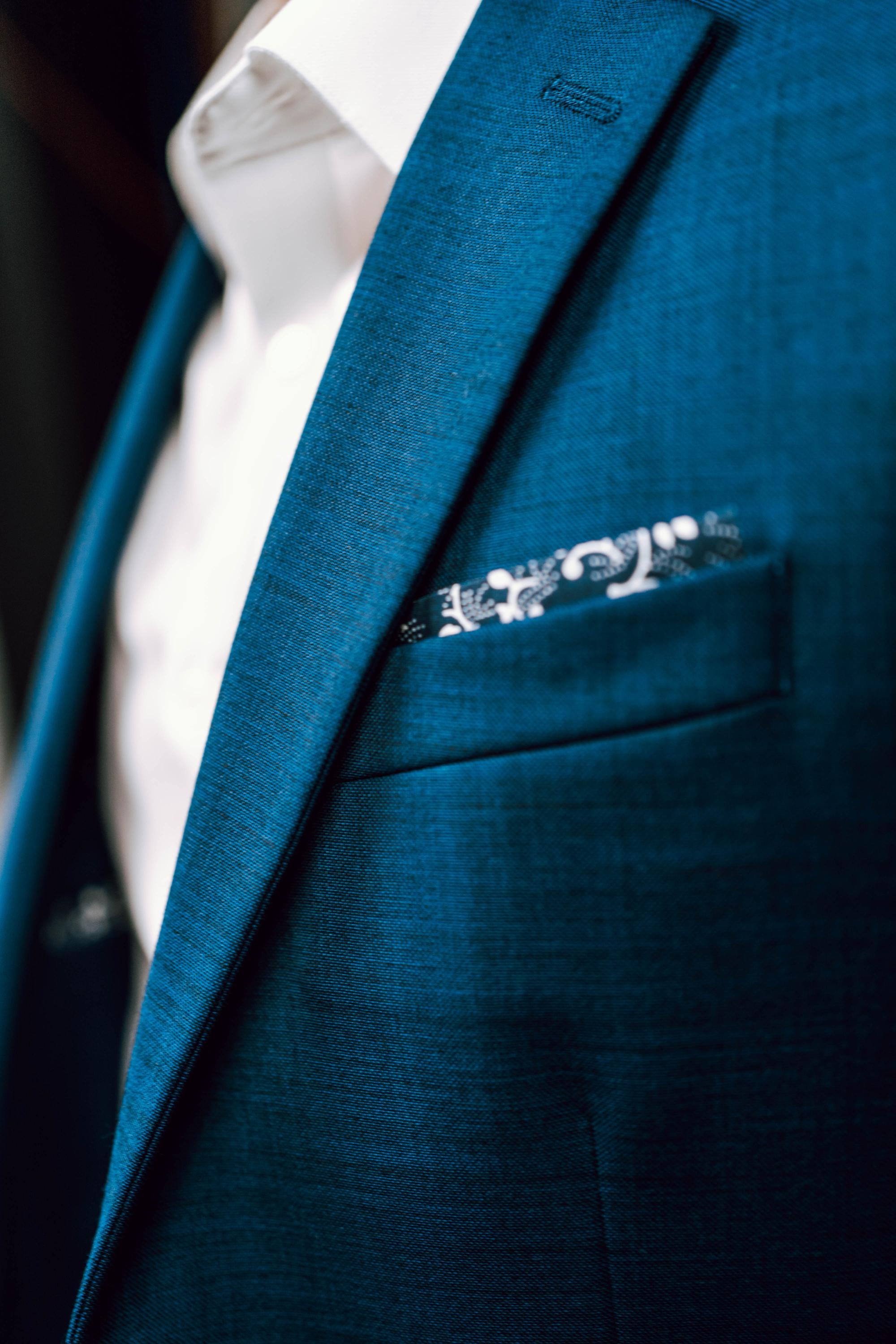A blue suit jacket carries a paisley hankerchief, with a white dress shirt underneath